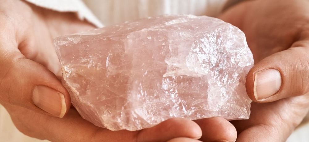 Hands holding a piece of rose quartz